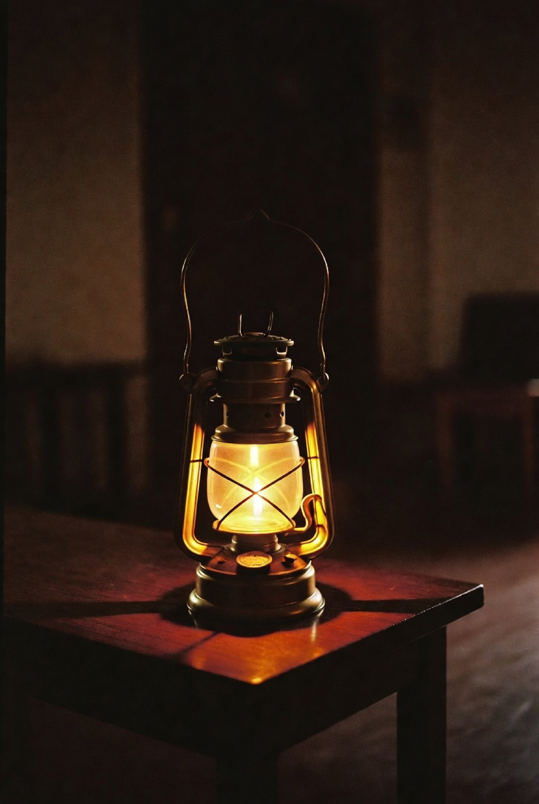 A lit lantern on a table in a dark room